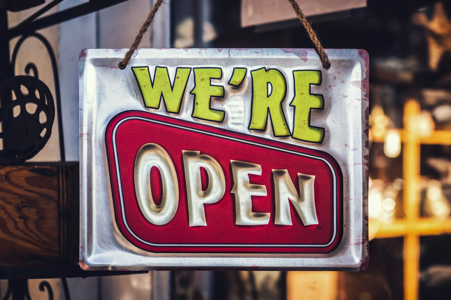 Retro-style "We're Open" sign hanging on a storefront, symbolising inviting retail signage